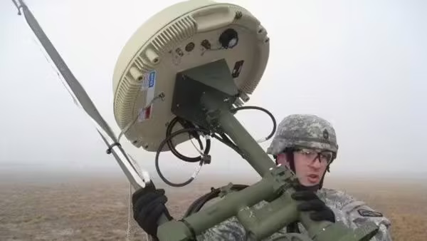 Photo of soldier operating a military signal jammer in the field, with antennas and equipment visible
